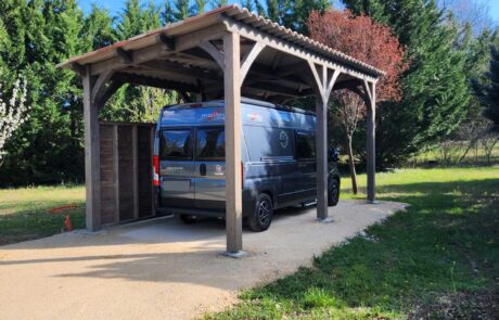 Image représentant un abri voiture Déco Charpente avec toiture en pente accueillant un camping-car.
